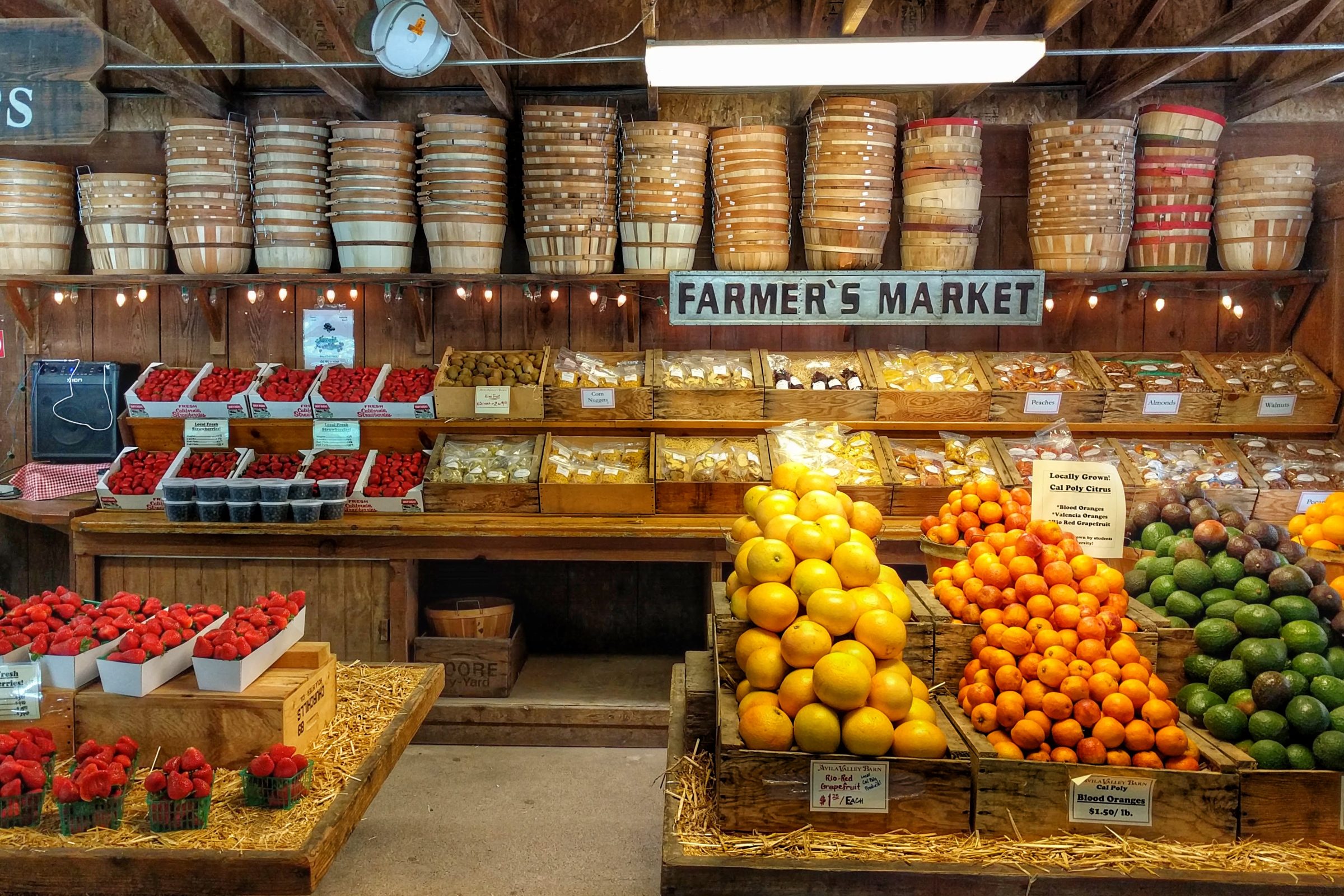 Strawberries, citrus, avocados and dried fruit under the Farmer's Market sign inside Avila Valley Barn