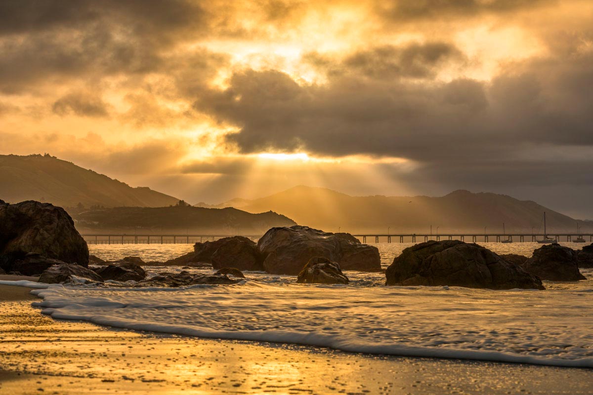 Golden rays of morning light over rocks at Avila Beach
