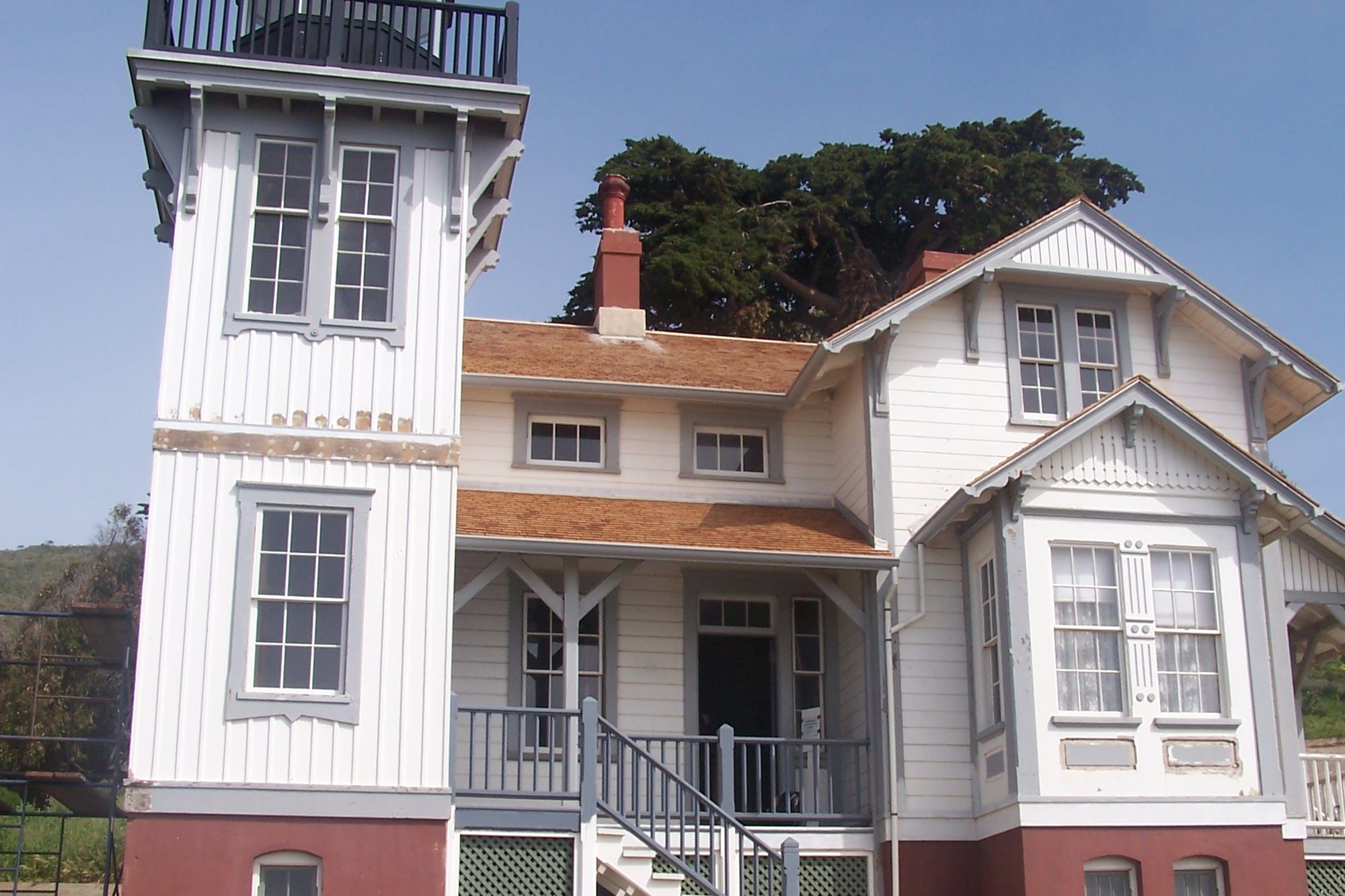 The restored 1889 Point San Luis Lighthouse, a white Victorian keeper's house with its square light tower, under a clear blue sky
