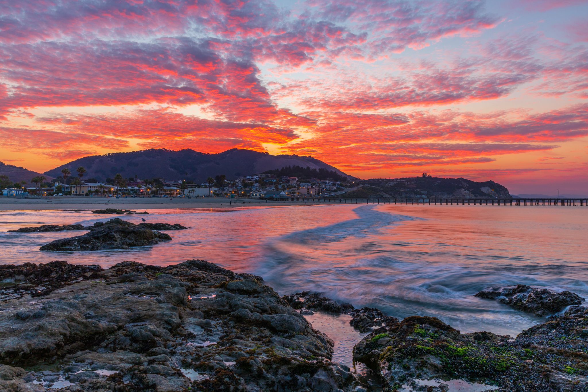 Pink sunrise sky over the town of Avila Beach and the pier