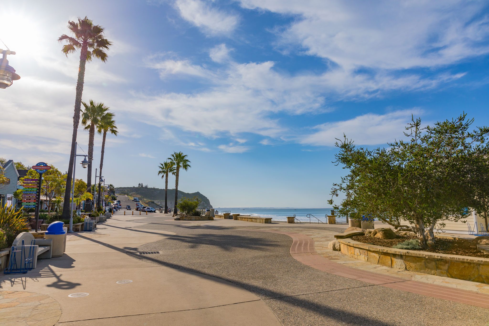 The palm-lined promenade along Front Street, with the Landing Passage shop sign and the beach