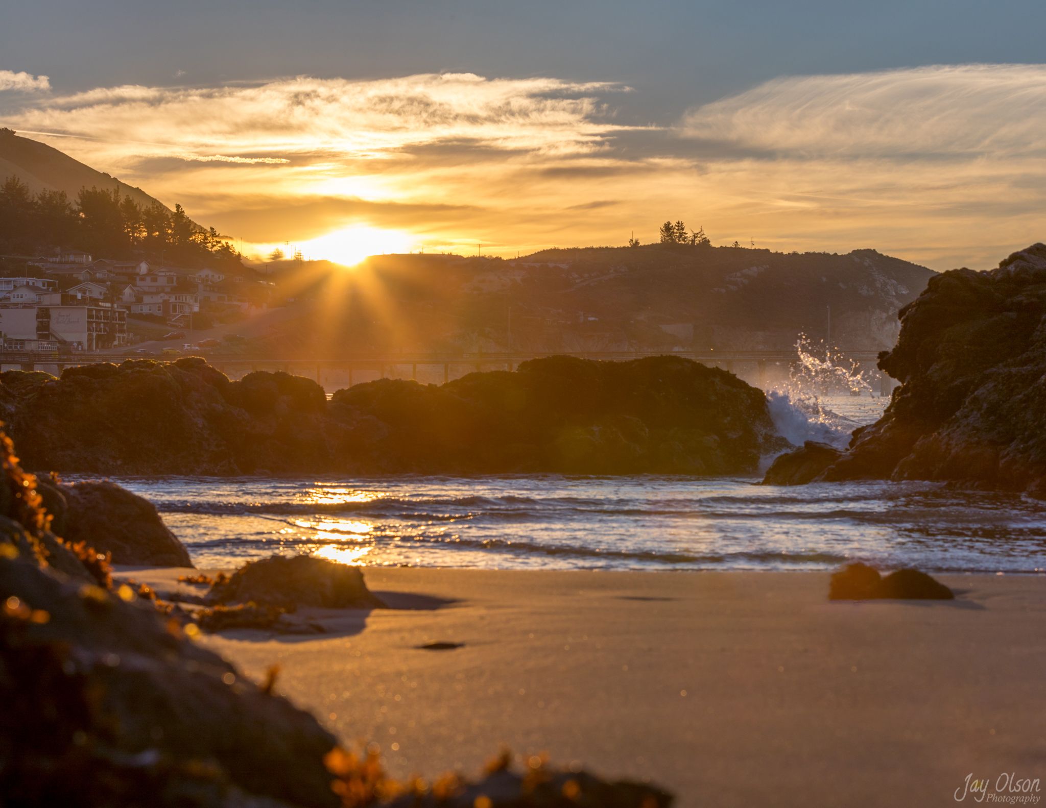 The sun bursting over shoreline rocks in Avila Beach