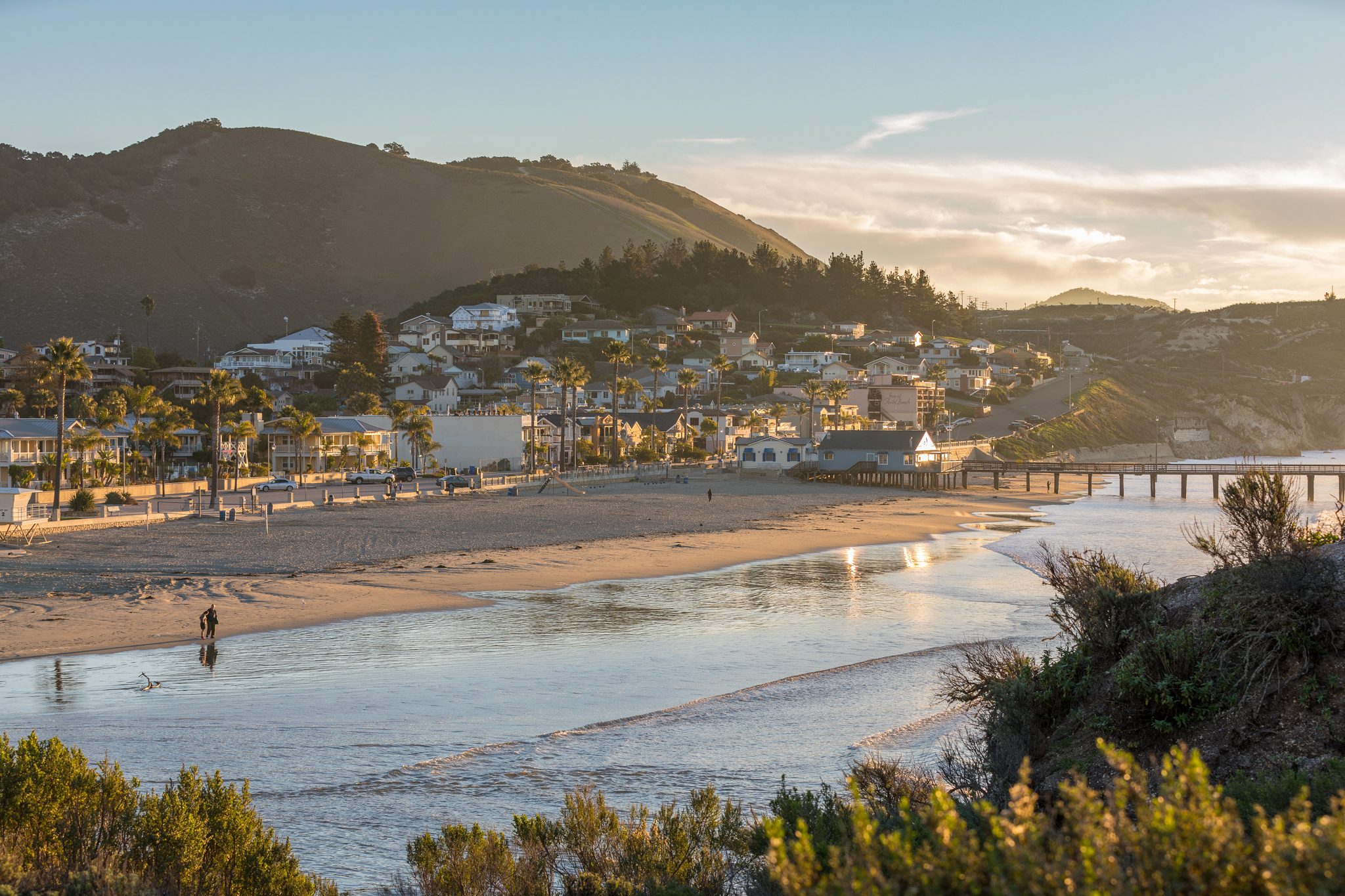 Houses climbing the hill above Avila Beach in late-day light, with the pier at right