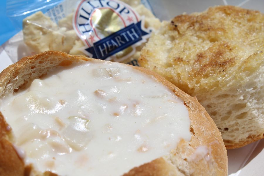 Clam chowder in a toasted sourdough bread bowl with a packet of oyster crackers