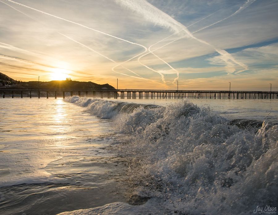 Jet contrails over the surf at Avila Beach at dawn