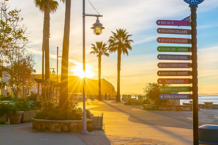 The Avila Beach Landing Passage sign pointing to shops and restaurants at sunrise