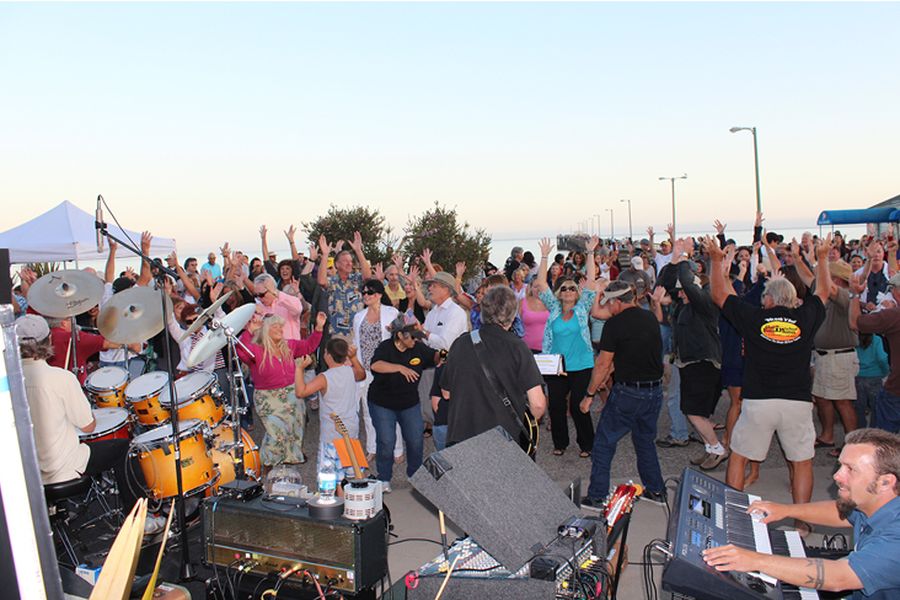 A crowd dancing to a live band on the promenade at the Friday farmers market