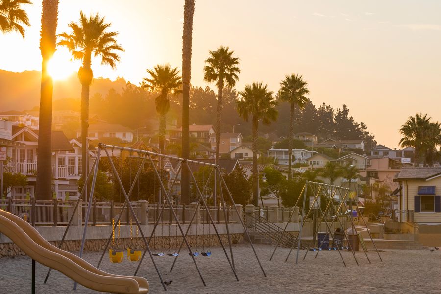 The beach playground swings and slide below Front Street in early golden light