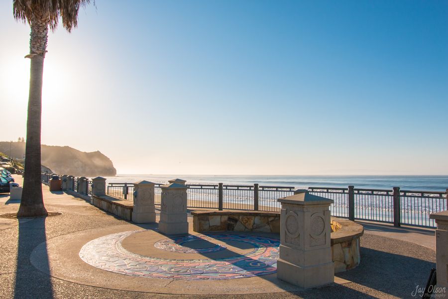 The tiled mosaic circle and stone pillars on the Avila Beach promenade on a clear morning