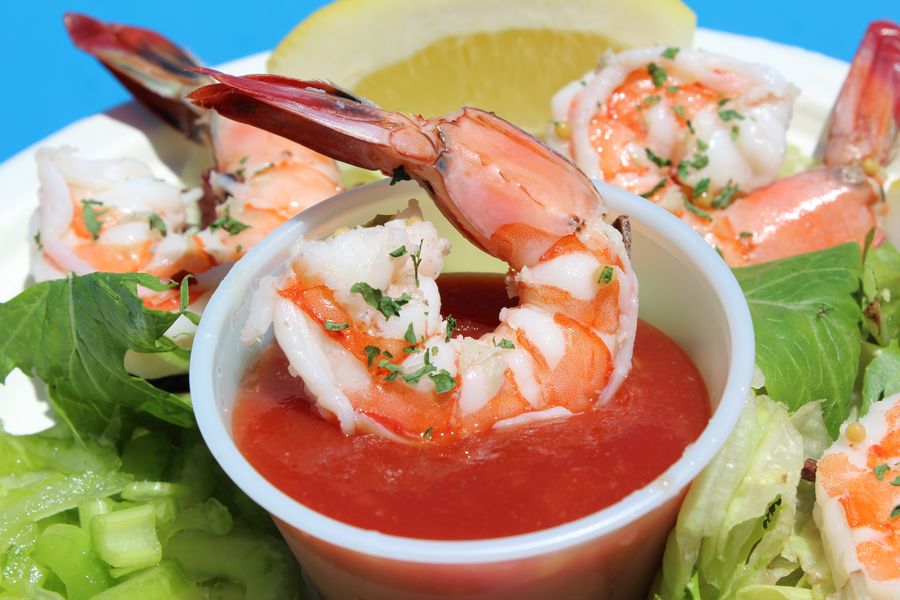 Close-up of a shrimp cocktail with cocktail sauce, lemon and lettuce