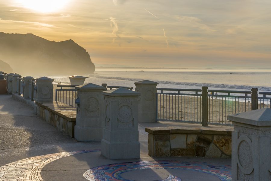 Morning sun over the headland and the tiled circle on the Avila Beach promenade